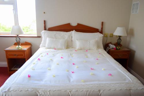 
a bed with a white comforter and pillows at Rhu Glenn Hotel in Waterford
