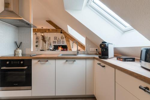 une cuisine avec des armoires blanches et un four noir dans l'établissement Le Monti-Nid - Authentique et Chaleureux, à Montigny-lès-Metz