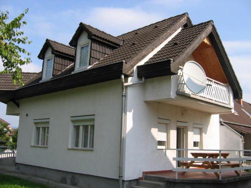 a white house with a balcony and a picnic table at Barzsó Vendégház in Bogács