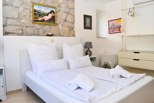 a white bed in a room with a stone wall at Villa Columba - 4 Star Deluxe Apartments - Sea-Front & Panorama View in Makarska