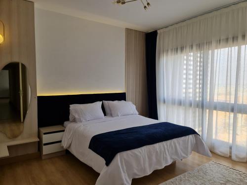a bedroom with a large bed and a large window at Madinaty Elite Living Apartment in New cairo