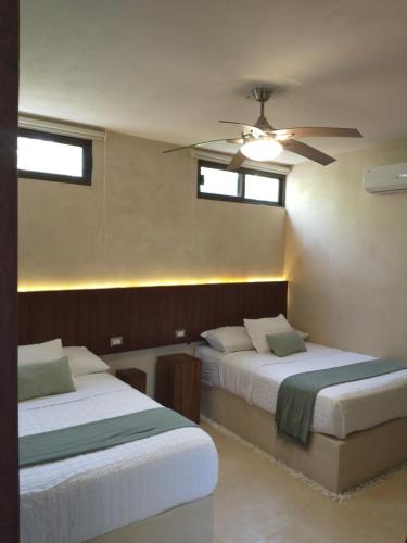 a bedroom with two beds and a ceiling fan at Cssa Kareli Holbox in Holbox Island