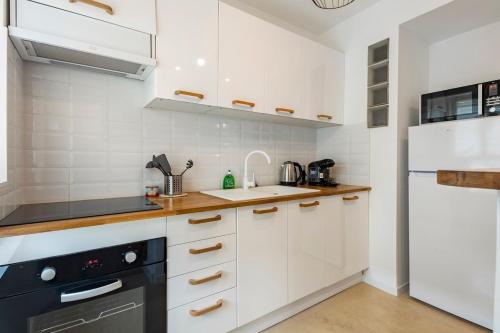 une cuisine avec des armoires blanches et un appareil noir dans l'établissement Le Cosy des Remparts! Aigues-Mortes, à Aigues-Mortes