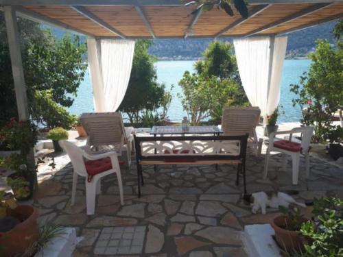 a patio with a table and chairs and a cat laying on the ground at Geni Bay in Yenion