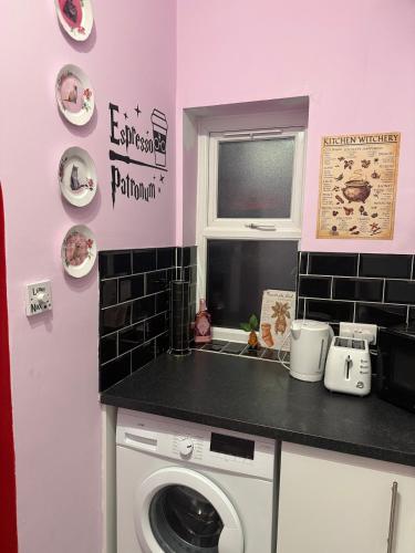 a kitchen with a washing machine and a window at Gryffindor Common Room- Warner Bros Studios & London in Watford