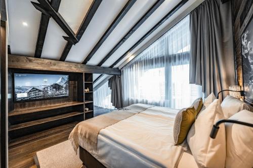 a bedroom with a large bed and a tv at Wellness Hotel Alpenhof in Zermatt