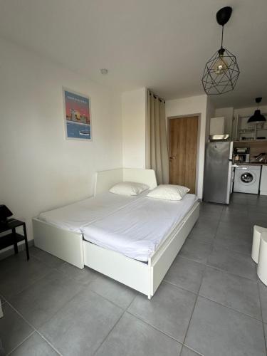 Ce lit blanc se trouve dans un dortoir doté d'une cuisine. dans l'établissement Studio proche de la plage et du centre ville, à Palavas-les-Flots