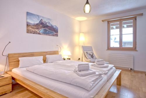 Apartment Alpin DG - GRIWA RENT AG في جريندلفالد: غرفة نوم بها سرير أبيض كبير وكرسي