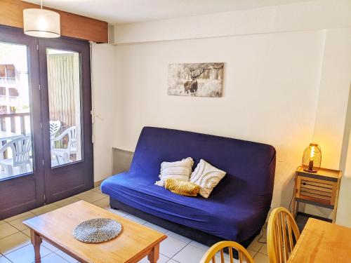 a blue couch in a living room with a table at Appt T3 calme bord du lac avec piscine in Loudenvielle