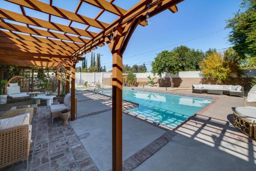 a wooden pergola over a swimming pool at Outdoor Oasis with Hot Tub Luxe Woodland Hills Gem in Woodland Hills