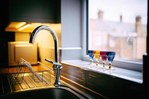 a kitchen sink with two wine glasses on a window at Coalminer's Cottage in Gateshead