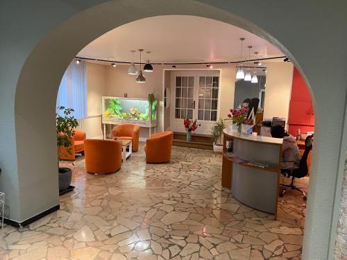 an archway in a lobby with orange chairs and a fish tank at Nouvel Hotel in Lons-le-Saunier