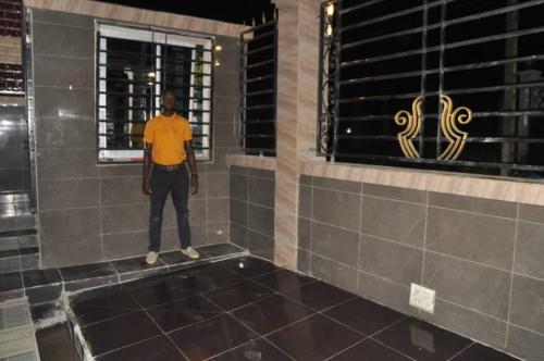 a man standing in a bathroom looking out a window at Dortmund Appartment in Douala