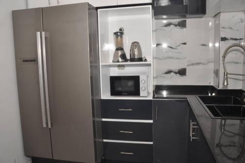 a kitchen with a refrigerator and a microwave at Dortmund Appartment in Douala