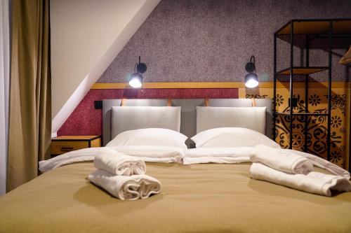 a large bed with two white towels on it at Leśny Wierch luxury spa villas in Bukowina Tatrzańska