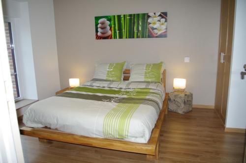 um quarto com uma cama com lençóis verdes e brancos em Gîte Des Hirondelles em Pipriac