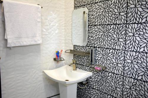 ラーワルピンディーにあるMehmaan Lodgeのバスルーム(シンク、白黒の壁紙付)