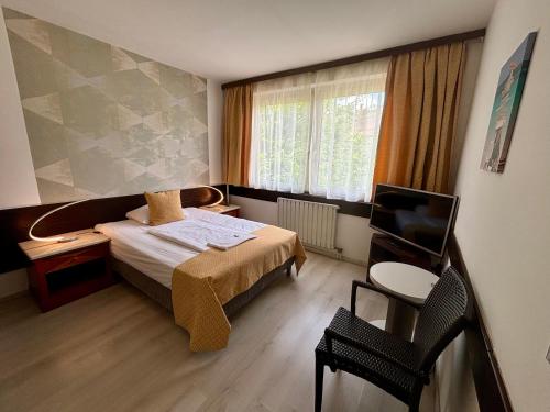 a bedroom with a bed and a desk and a television at Hotel Gloria Budapest City Center in Budapest