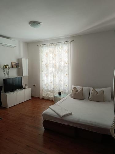 a white bedroom with a bed and a window at lino in Ivan Dolac
