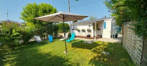 a yard with an umbrella and a house at Mobile home climatisé au Lac de Lougratte in Lougratte