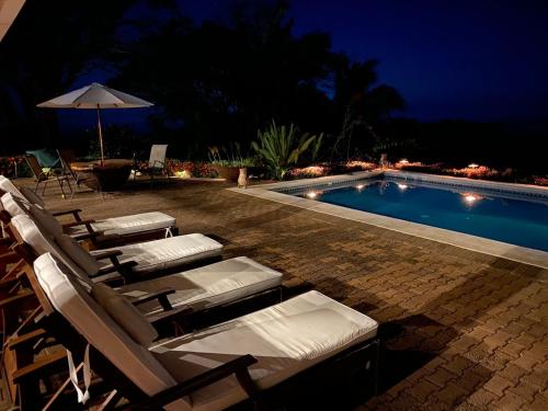 a group of lounge chairs next to a swimming pool at night at Casa La Paila -- Amazing ocean & mountain views! Staff included! in Carrillo