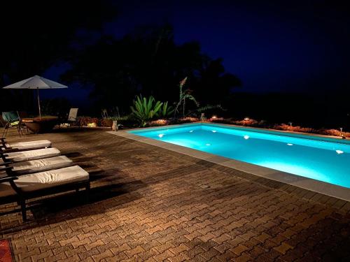 a swimming pool at night with chairs and an umbrella at Casa La Paila -- Amazing ocean & mountain views! Staff included! in Carrillo