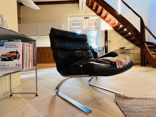a black leather chair sitting in a living room at ARTvacanza Atelierhaus Edenkoben in Edenkoben