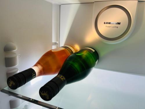 two bottles of wine on a shelf next to a clock at ARTvacanza Atelierhaus Edenkoben in Edenkoben