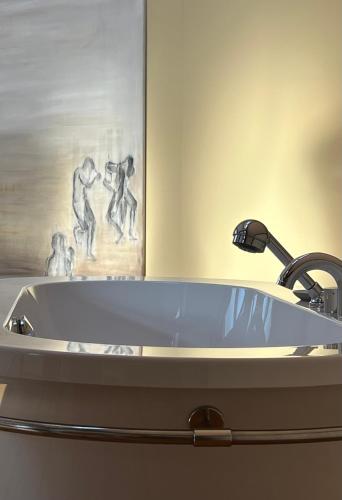 a bath tub in a bathroom with a painting at ARTvacanza Atelierhaus Edenkoben in Edenkoben