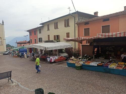 a man walking past an outdoor market in a town at Blondie House - Pool & LakeView - by Host4U in Fonteno