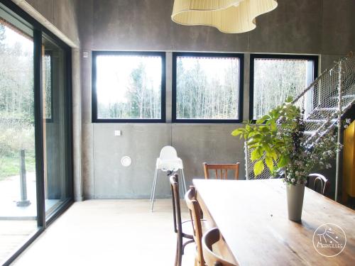 d'une salle à manger avec une table et quelques fenêtres. dans l'établissement Ecogîte autonome en pleine forêt à La Chapelle en Vercors, à La Chapelle-en-Vercors