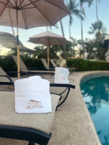 two tables with umbrellas next to a swimming pool at Villas El Dorado in Rincon de Guayabitos