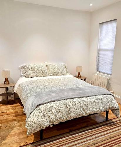 a white bedroom with a bed and two tables at Jersey City Private Entire Apartment - 30 Minutes From Wall St New York City in Jersey City