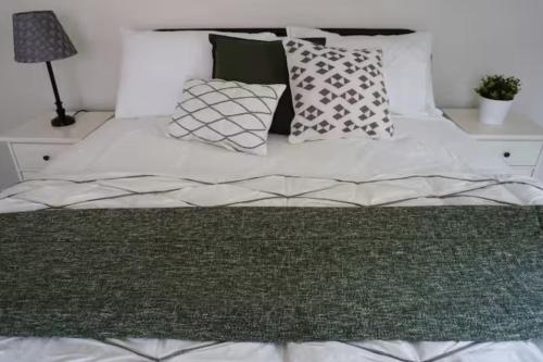 a bed with a green blanket and pillows on it at Chic Country Home in the Woods with Hot Tub in Ruidoso