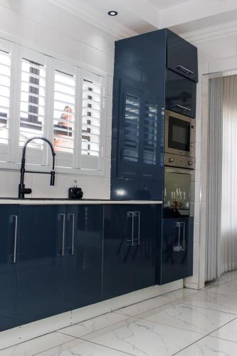 a kitchen with blue cabinets and a sink and a microwave at 28 Wilfred Villa in Johannesburg