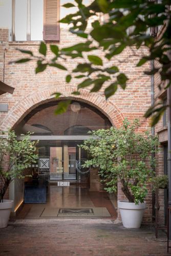 an entrance to a brick building with two potted trees at Maxxim Hotel & Loft in Ferrara