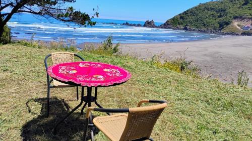 a table and two chairs sitting next to a beach at Cabaña con acceso a playa en Mehuin in Mehuín