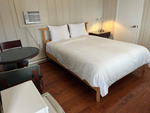 a bedroom with a large bed with a table and a chair at Motel Clair Mont in Sainte-Agathe-des-Monts