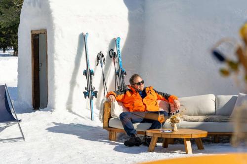 a man sitting on a couch in the snow at Grand Hotel des Bains Kempinski in St. Moritz