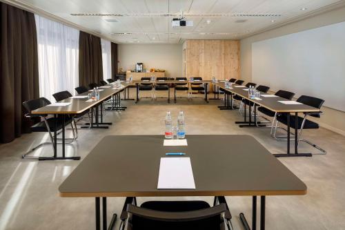 a conference room with tables and chairs and a whiteboard at Hotel Allegra Lodge in Kloten