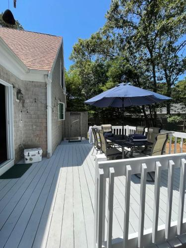 a wooden deck with a table and an umbrella at Cozy Bungalow Close to Downtown in Harwich