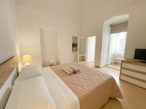 a white bedroom with a large bed and a television at L'Armonia - "La Capasa" in Noci
