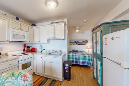 a kitchen with white cabinets and a sink and a refrigerator at Ocean Sands 136 in Atlantic Beach