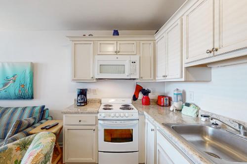 a kitchen with white cabinets and a stove and a sink at Ocean Sands 136 in Atlantic Beach