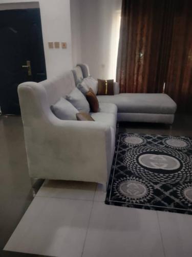 a white couch in a living room with a rug at Whitney white 1bedroom shortlet apartment 24hr light Stadium Road N55,000 in Port Harcourt