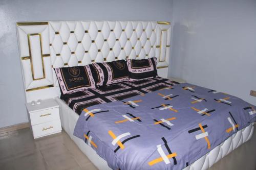 a bed with a blue comforter with crosses on it at Whitney white 1bedroom shortlet apartment 24hr light Stadium Road N55,000 in Port Harcourt