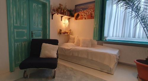 a bedroom with a bed and a chair and a window at Csacsiország Vendégház in Nógrádsáp