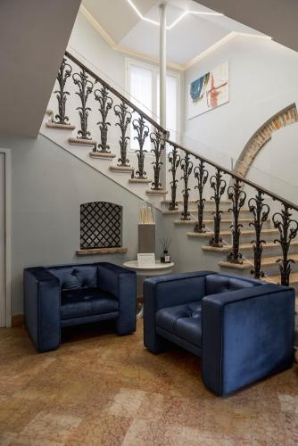 a living room with two blue couches and a staircase at Maxxim Hotel & Loft in Ferrara