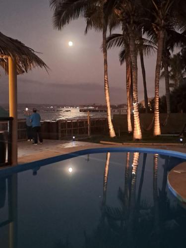 a man standing next to a swimming pool at night at H0TELIER Home, Máncora in Máncora