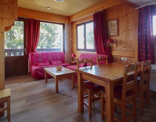 un salon avec une table et un canapé rouge dans l'établissement La Grande Cordée - Cœur d'Alpage, à Combloux